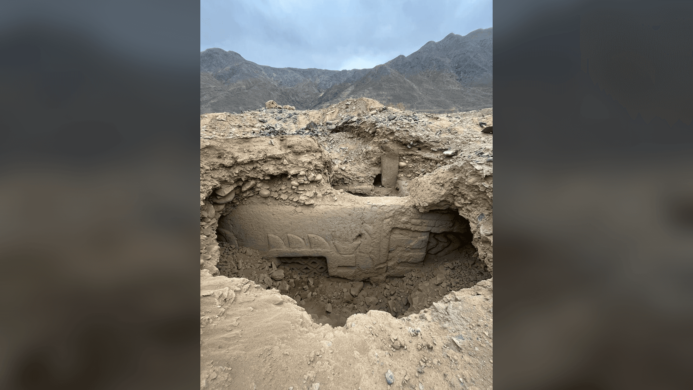 an archaeological dig revealing a large 3D mural with a backdrop of the Andes mountains