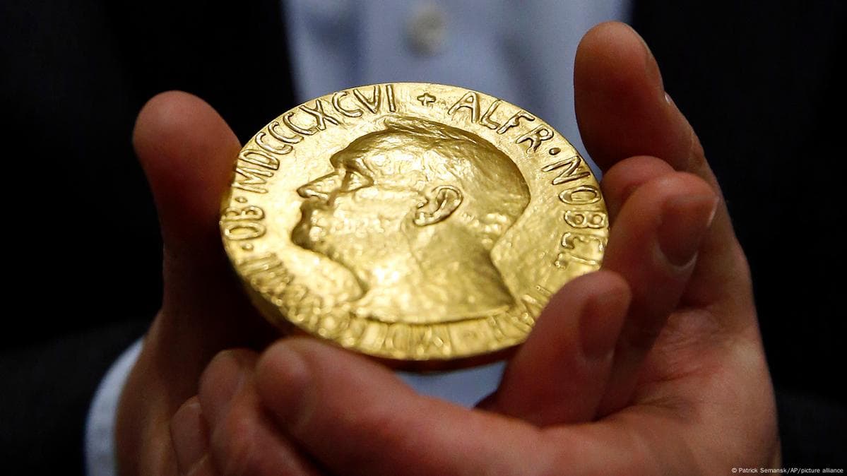 Đôi tay nam giới cầm huy chương vàng Giải Nobel