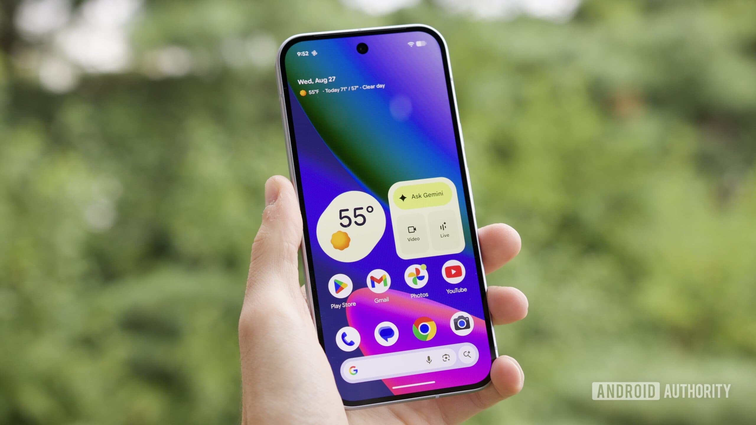 Ai đó cầm Google Pixel 10 với màn hình bật, hiển thị màn hình chính.