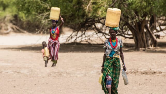 Hai phụ nữ Turkana khiêng nước qua vùng đất khô cằn