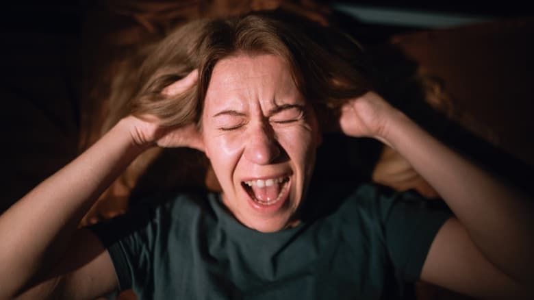 Một người phụ nữ la hét khi nằm trên giường